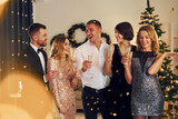 Fototapeta  - Cheering with champagne. Group of people have a new year pary indoors together