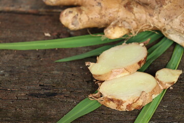 Wall Mural - Ginger root and green leaves on wood background