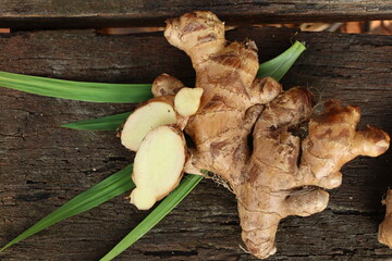 Wall Mural - Ginger root and green leaves on wood background