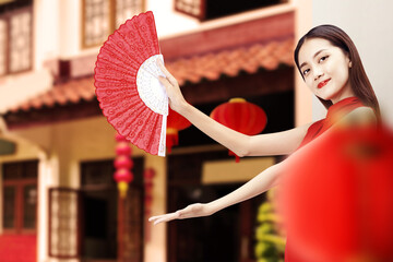 Wall Mural - Asian Chinese woman in a cheongsam dress holding fan with open palm showing something