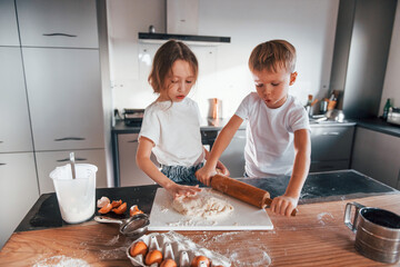 Two people together. Little boy and girl preparing Christmas cookies on the kitchen