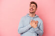 © Asier - Young caucasian man isolated on pink background laughing keeping hands on heart, concept of happiness.