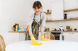 © Drobot Dean - White young woman in gloves smiling while cleaning table