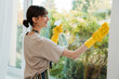 © Drobot Dean - White young woman in gloves smiling while cleaning window