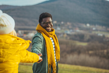 Woman and man holding hands on a golden yellow meadow. There was an orange evening light shining down on both of them in soft tones. Feelings of love and romance.