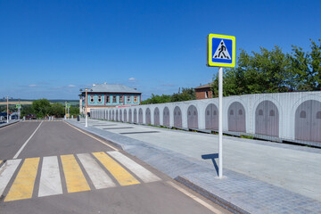 Zebra crossing across the road with a small-shaped sign in the city of Zaraysk on a summer day