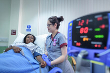 Nurse Checking Patients Blood Pressure On Hospital Ward