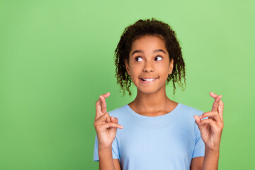 Portrait of attractive trendy cheerful girl crossed fingers praying copy space isolated over green pastel color background