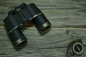 old binoculars and compass on a wooden background.banner.