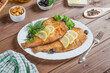 Fried flounder with lemon and herbs on a white plate on a dark wooden background