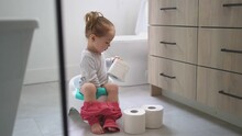 An Adorable Young Baby Child Sitting And Learning How To Use The Toilet 