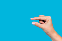 Closeup View Stock Photography  Of Beautiful White Manicured Female Hand Showing Small Size Of Virtual Invisible Object With Help Of Two Fingers Isolated On Blue Background