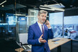 © Liubomir - Successful boss working in a modern office, gray-haired businessman talking on the phone