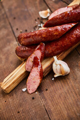 Wall Mural - Homemade sausage with garlic cut into slices lies on a wooden table on a cutting board with spices and garlic. Traditional sausage, ready to eat, delicious breakfast. 