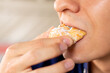 © Anderson Piza - Man's mouth biting a sweet chouquette. Young adult eating a Colombian sweet bread.