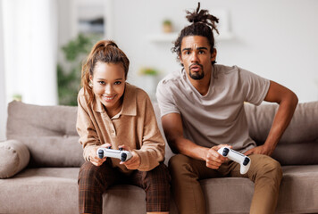 Wall Mural - African american couple laugh and play video games together using a video game console