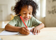 © JenkoAtaman - Smiling african american child school boy doing homework while sitting at desk at home