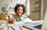 Fototapeta Przestrzenne - Smiling african american child school boy studying online on laptop at home