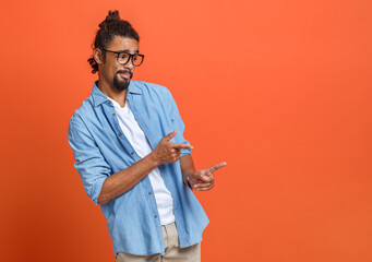 Young happy african american man in glasses pointing with forefinger at copy space