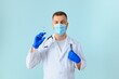 © Serhii - Vaccination against coronavirus. Testing COVID-19 vaccines. A male doctor in a medical mask fills a syringe the with a COVID-19 vaccine on a blue background. Doctor's hands hold a syringe close-up.