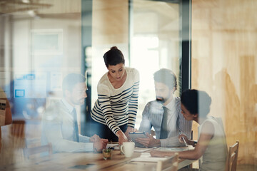 Poster - Success begins in this office. Through the glass shot of a group of colleagues working together in an office.