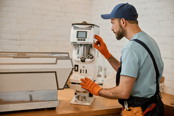 Canvas Print - Repairman checking professional coffee maker in cafe