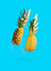 Wall Mural - Sliced juicy pineapple with water splash on pastel blue background. Minimal fruit concept. Modern food composition.