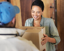 It's Finally Arrived. Shot Of A Smiling Young Woman Standing At Her Front Door Receiving A Package From A Courier.
