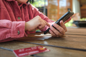 Poster - woman shopping online with credit card at coffee shop in outdoor.close up hand holding smartphone
