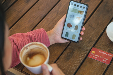 Poster - woman shopping online with credit card at coffee shop in outdoor.close up hand holding smartphone