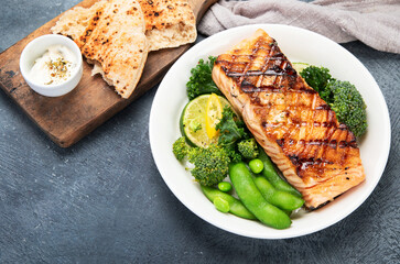 Wall Mural - Baked salmon with vegetables on dark background.