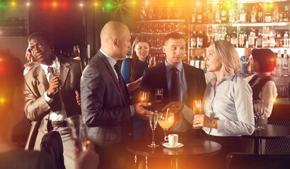 Wall Mural - Group of executives holding glasses with alcohol drinks and talking at office party