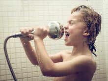 Boy Singing With Shower Head In Bathroom