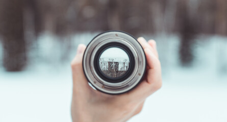 Wall Mural - Looking to the frozen lake in middle of forest through lens. Point of view. Selective focus.