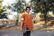 © Jacob Lund - Cheerful  teenage skateboarder holding his skateboard in an urban park