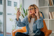 © carballo - middle aged adult woman at home talking by video conference with mobile phone