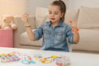 © New Africa - Cute little girl making beaded jewelry at table in room