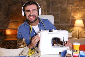 Wall Mural - Young man using sewing machine