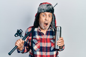 Canvas Print - Handsome mature man wearing fisherman equipment and thermo afraid and shocked with surprise and amazed expression, fear and excited face.