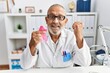 © Krakenimages.com - Mature doctor man holding pink cancer ribbon at the clinic screaming proud, celebrating victory and success very excited with raised arms