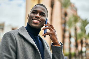 Young african american man smiling happy talking on the smartphone at the city