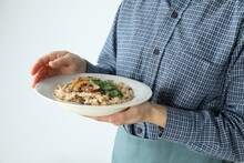 Woman In Apron Holds Plate Of Risotto With Mushrooms