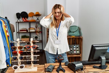 Canvas Print - Blonde beautiful young woman working as manager at retail boutique suffering from headache desperate and stressed because pain and migraine. hands on head.