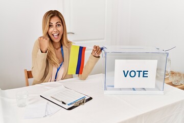 Sticker - Blonde beautiful young woman at political campaign election holding colombia flag screaming proud, celebrating victory and success very excited with raised arms