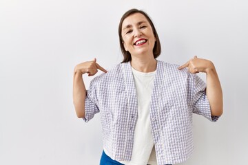 Wall Mural - Beautiful middle age hispanic woman standing over isolated background surprised pointing with hand finger to the side, open mouth amazed expression.