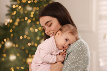 Wall Mural - Happy young mother with her cute baby against blurred festive lights. Winter holiday