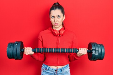 Sticker - Beautiful woman with blue eyes wearing sportswear using dumbbells skeptic and nervous, frowning upset because of problem. negative person.