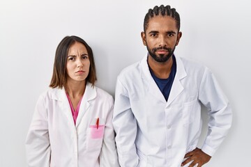 Wall Mural - Young hispanic doctors standing over white background skeptic and nervous, frowning upset because of problem. negative person.