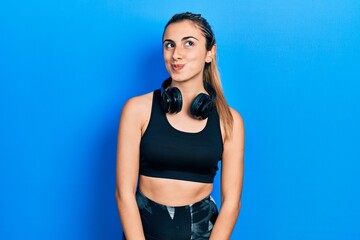 Sticker - Beautiful hispanic woman wearing gym clothes and using headphones smiling looking to the side and staring away thinking.