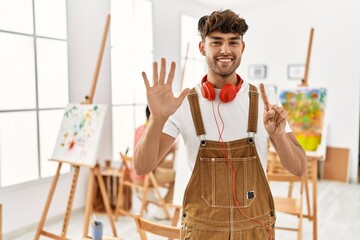 Canvas Print - Young hispanic man at art studio showing and pointing up with fingers number six while smiling confident and happy.